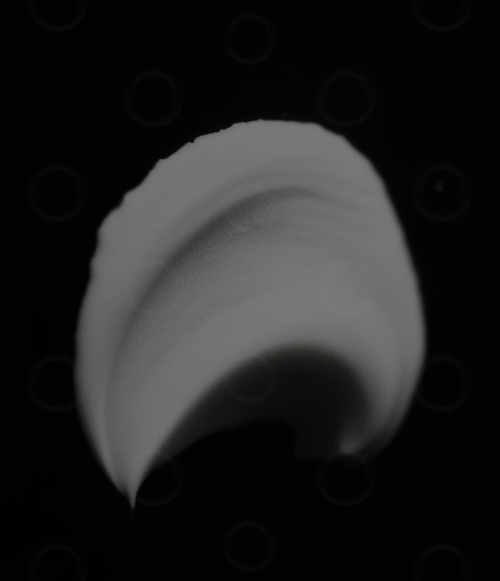 Monochrome white cosmetic cream on a black background.